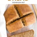 Half sliced loaf of Irish brown bread on wooden board.