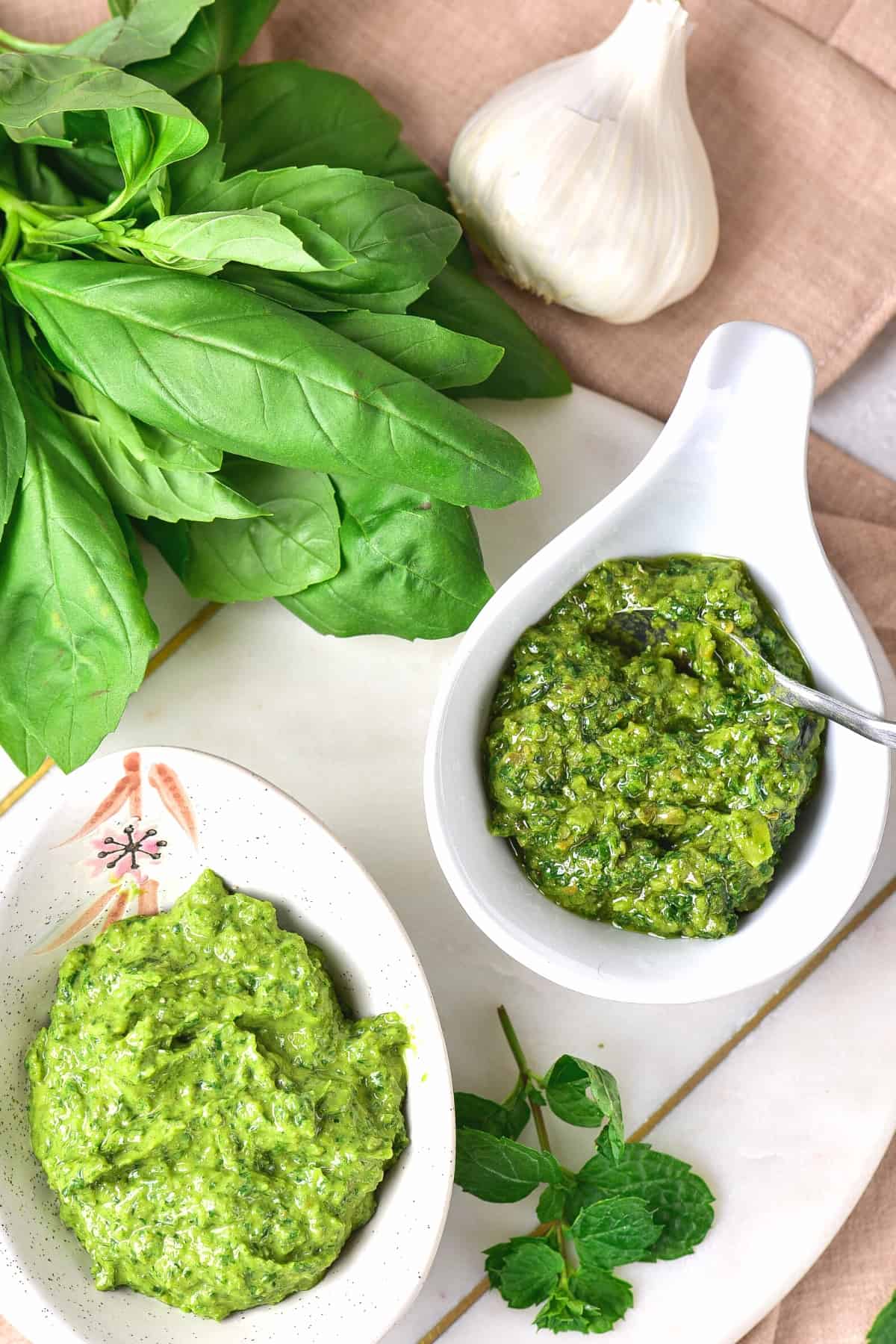 Salsa verde Italian style surrounded by fresh herbs on marble serving board.
