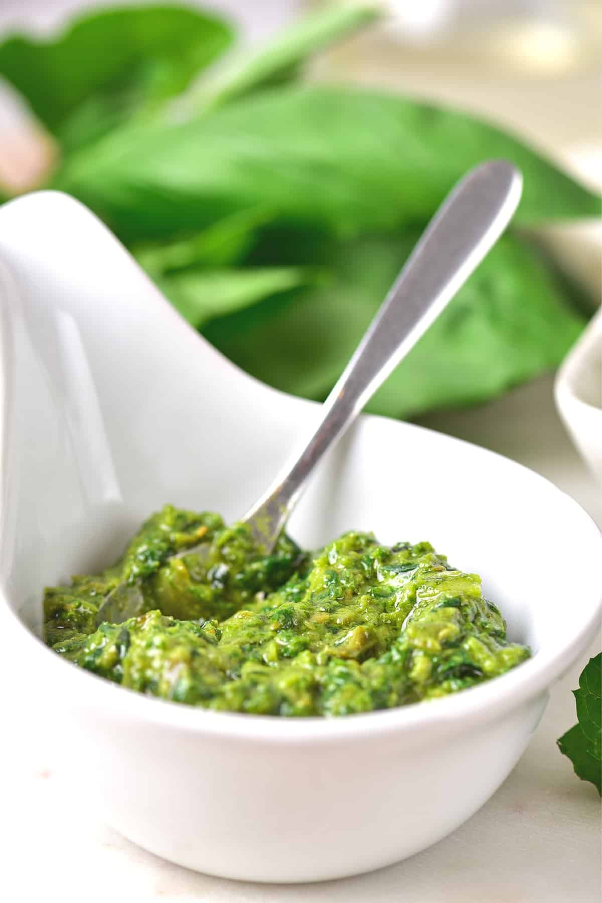 A spoon in a small bowl of green sauce.