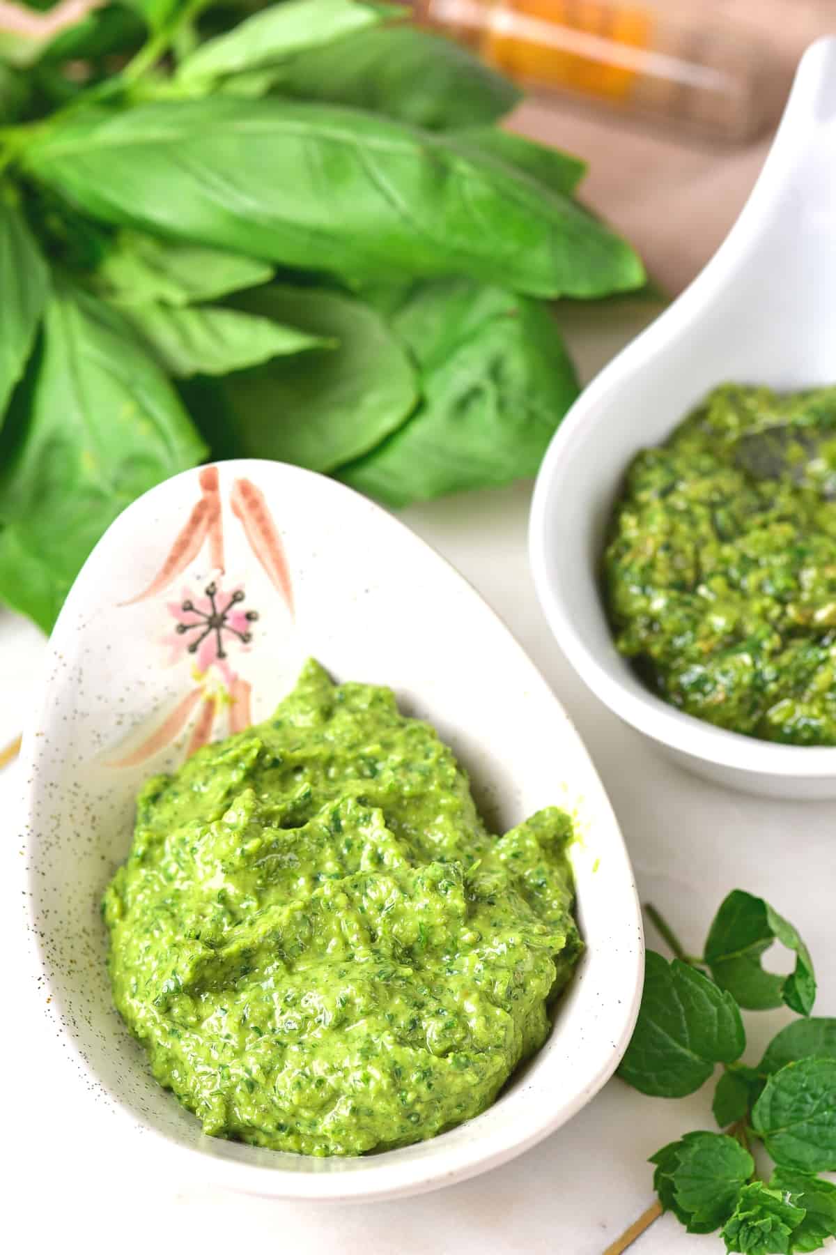 Up close shot of Italian green sauce in a small bowl surrounded by herbs.