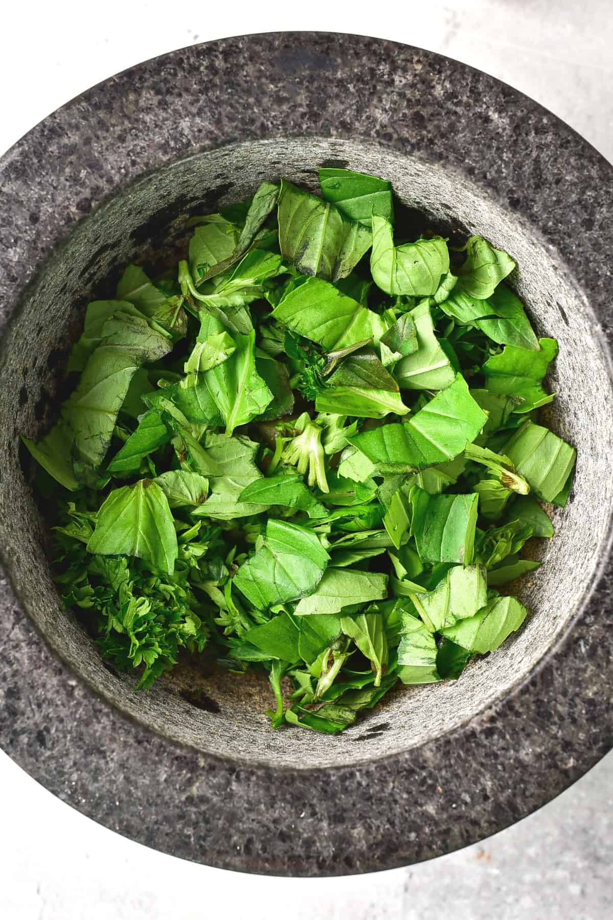 Chopped fresh herbs in a mortar.
