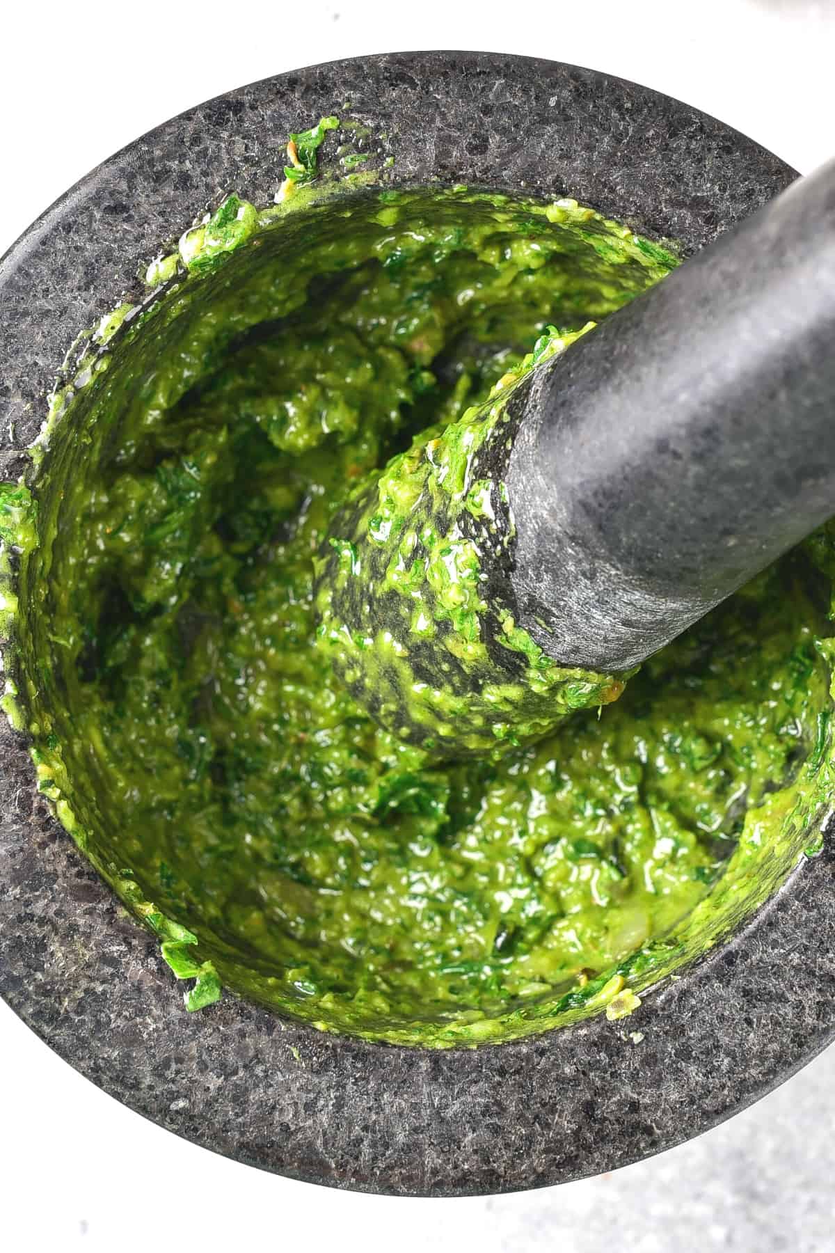 Grinding fresh herbs into a paste with a pestle and mortar.