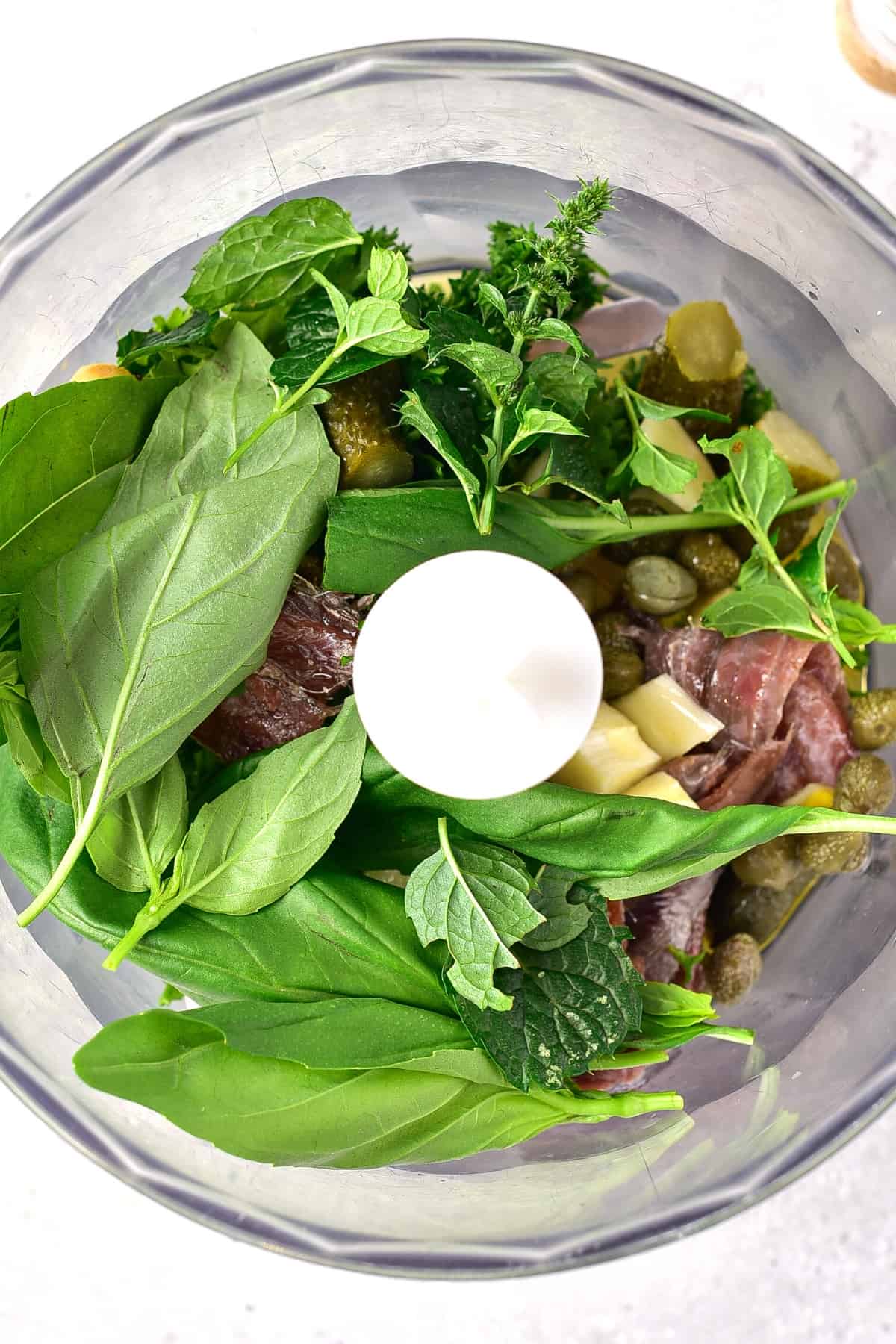Top down view of ingredients for Italian salsa verde in food processor.