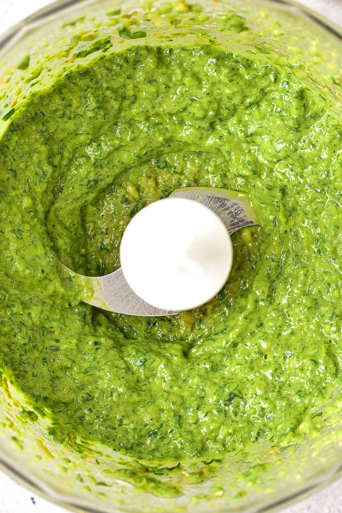 Up close view of processed salsa verde in food processor.