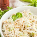 Up close view of a bowl of chicken salad and sliced jalapeños.