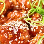 Up close view of korean fried chicken sprinkled with sesame seeds