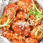 Up close view of korean fried chicken in parchment-lined bowl.