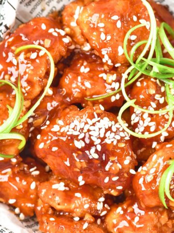Up close view of korean fried chicken in parchment-lined bowl.