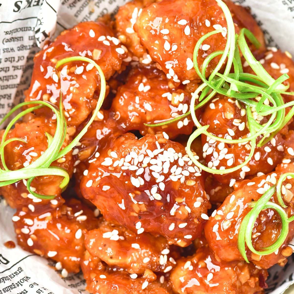 Up close view of korean fried chicken in parchment-lined bowl.