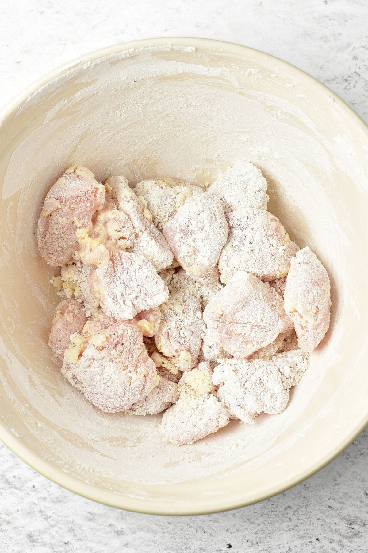 A bowl of cornstarch coated chicken pieces
