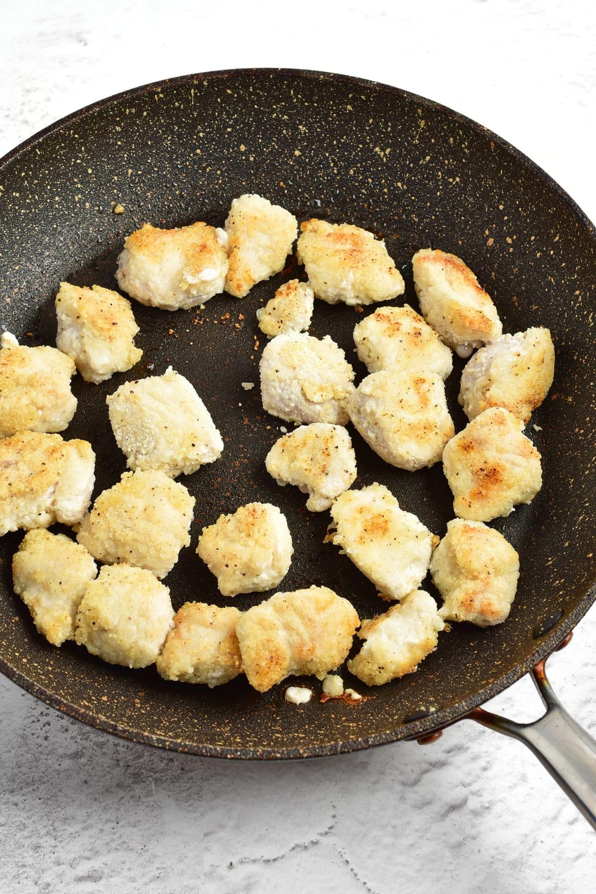 Pan-frying coated chicken pieces in skillet
