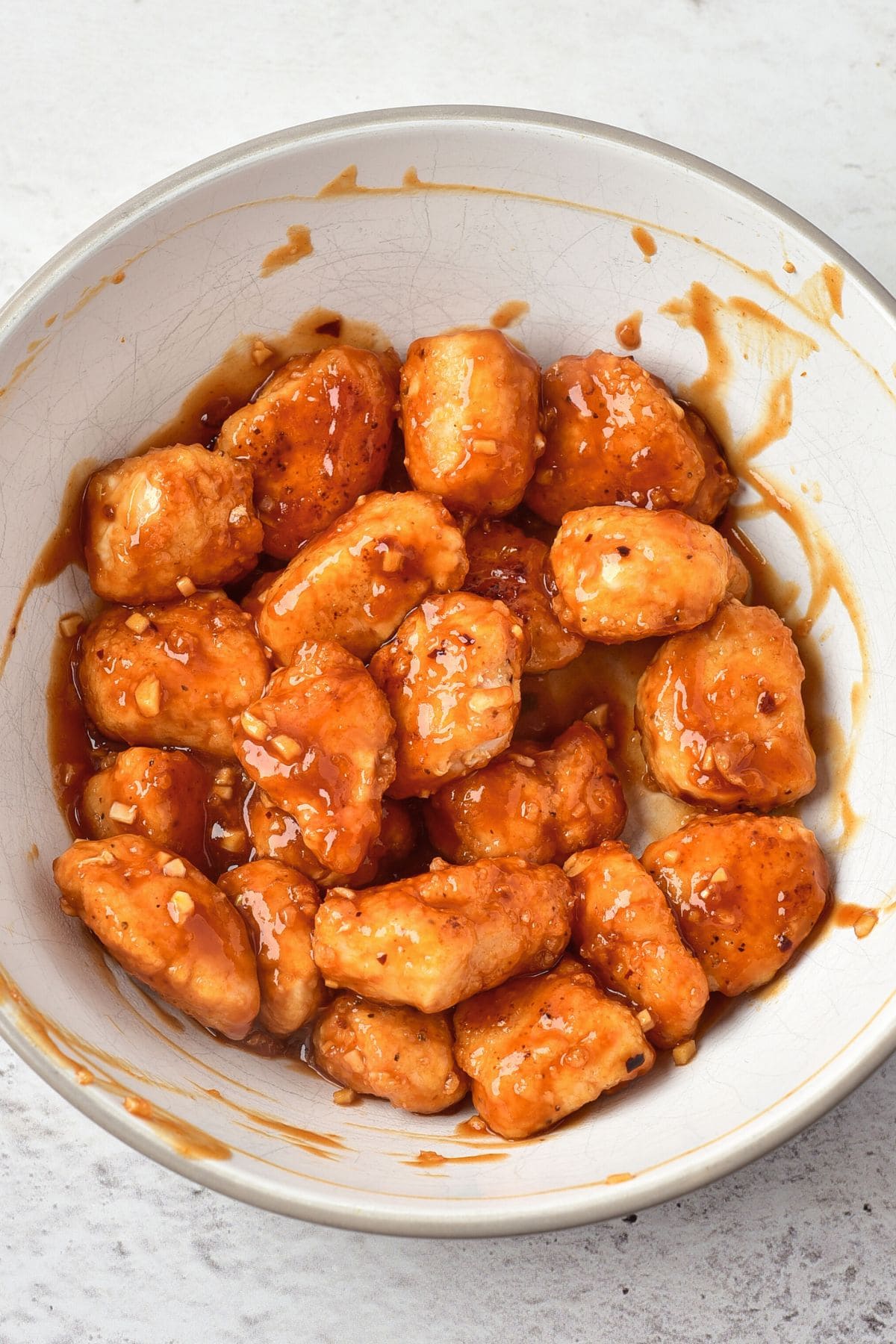 Tossing fried battered chicken in red sauce