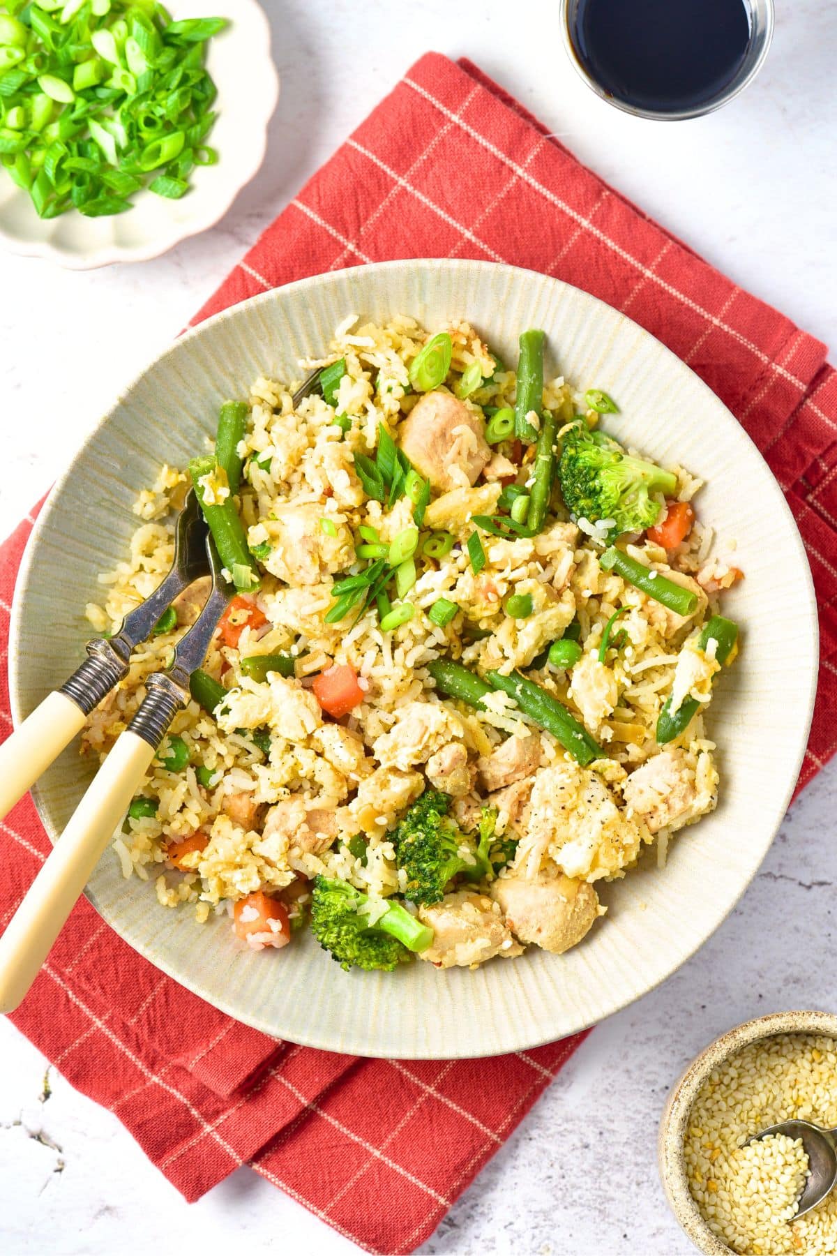 Top down view of fork and spoon in bowl of fried rice on red towel.