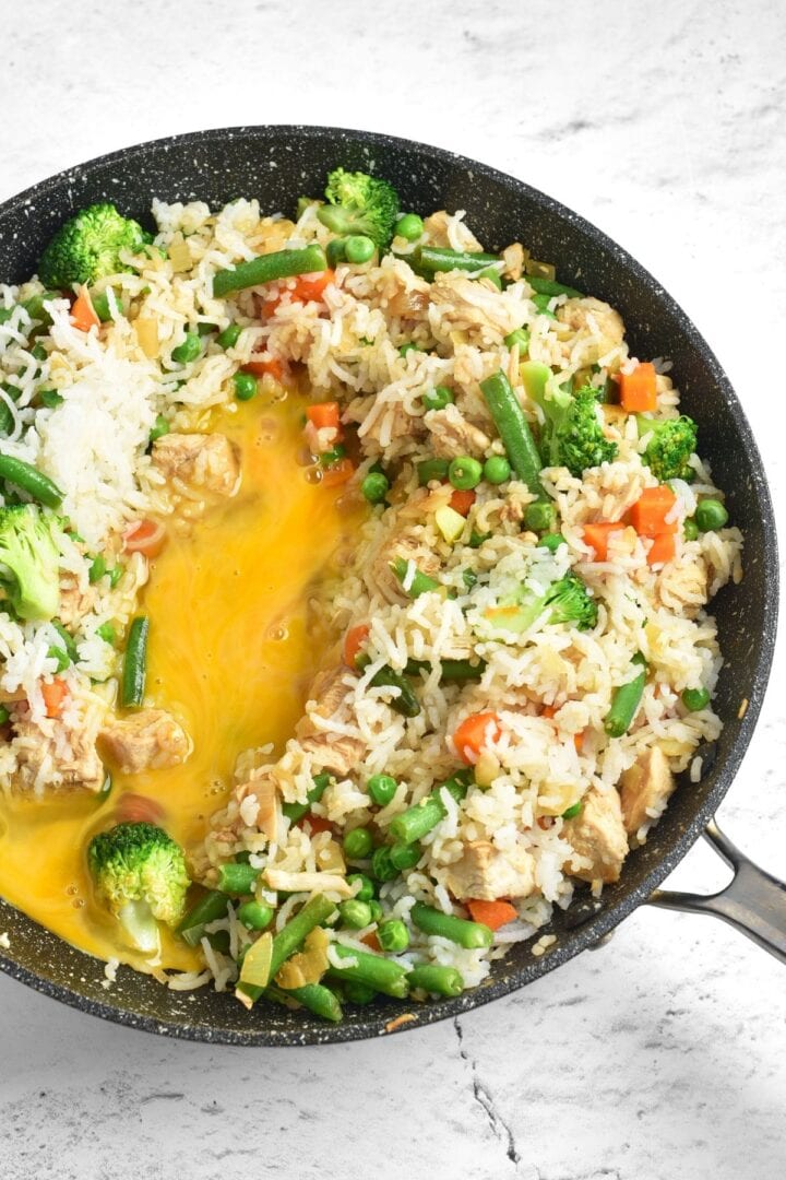 Beaten eggs in skillet with fried rice.