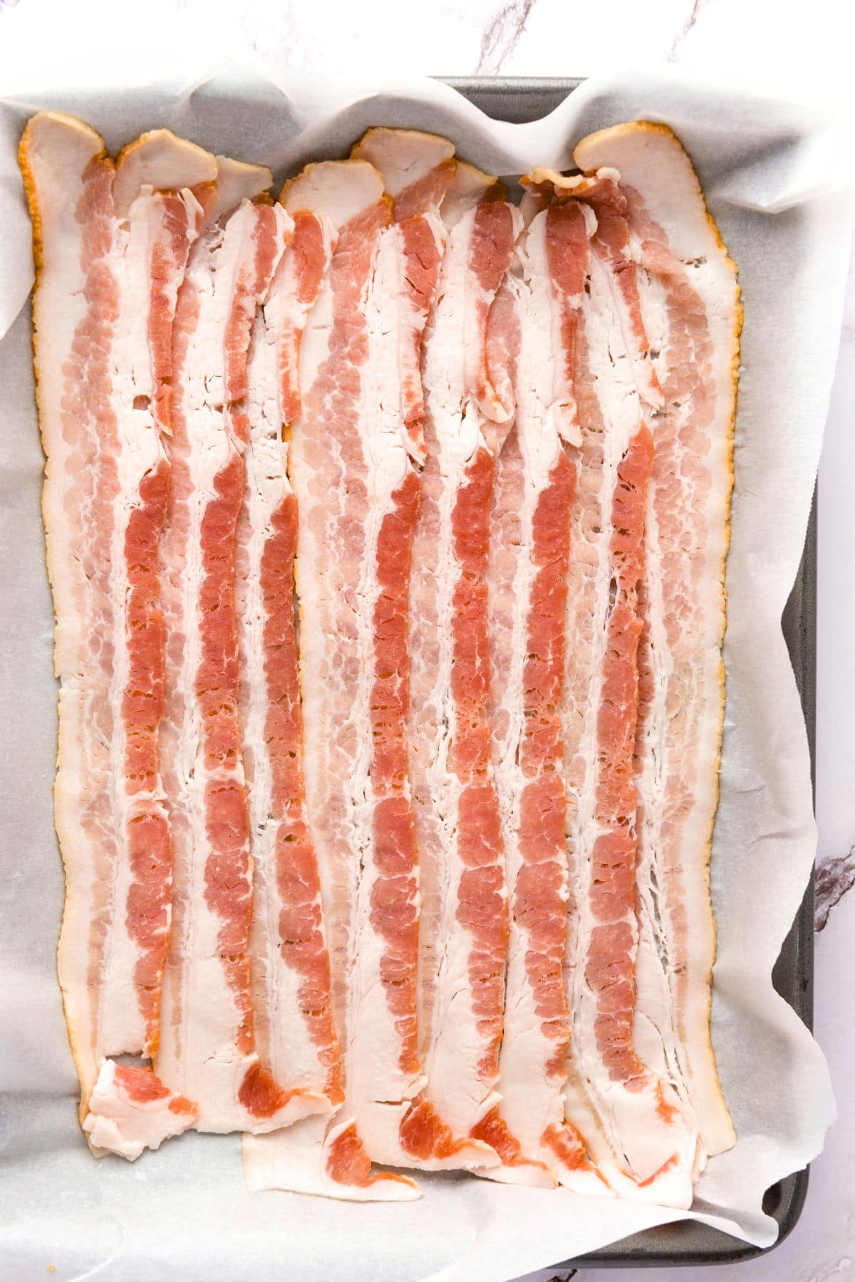 Bacon slices on parchment-lined baking sheet