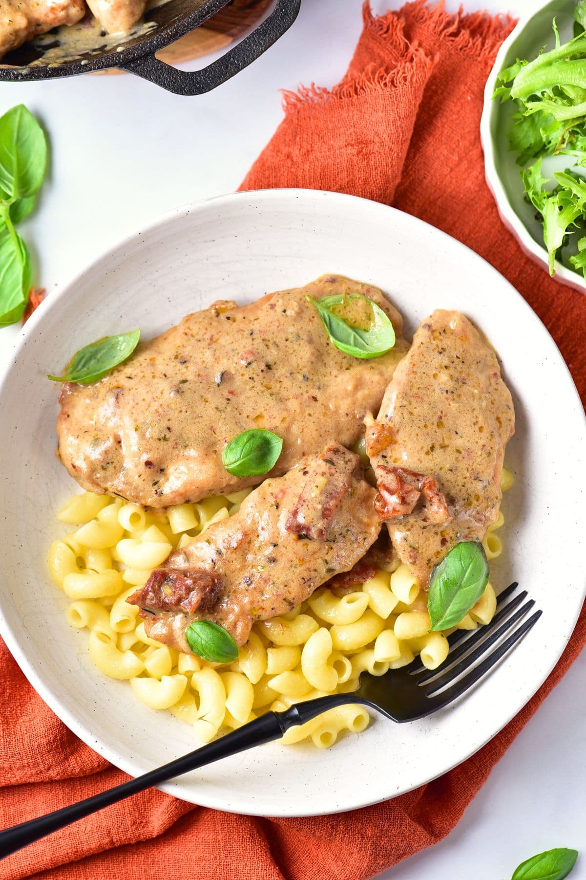 Marry me chicken pasta in a bowl topped with fresh basil leaves.