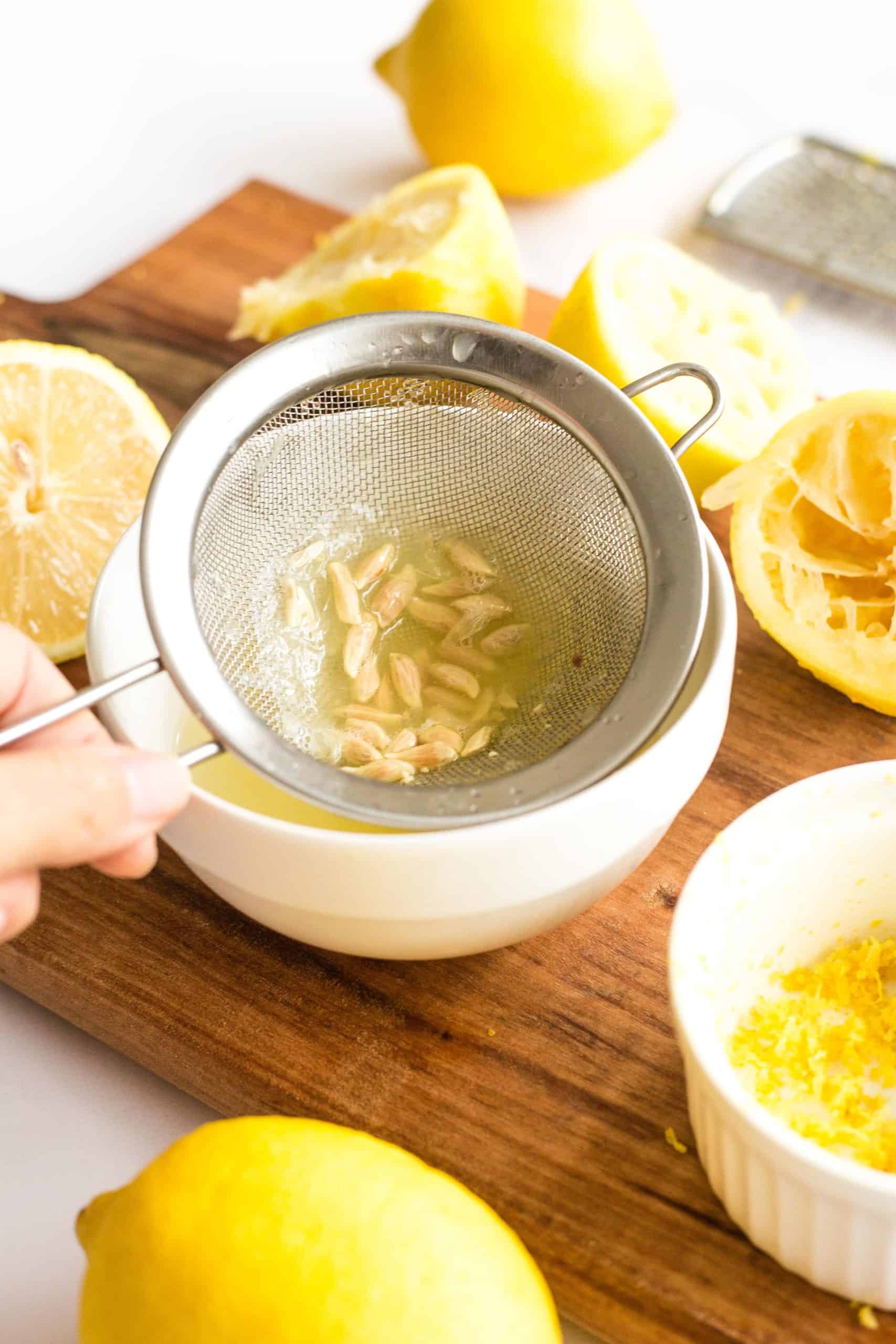 Using a strainer to separate lemon seeds from lemon juice.
