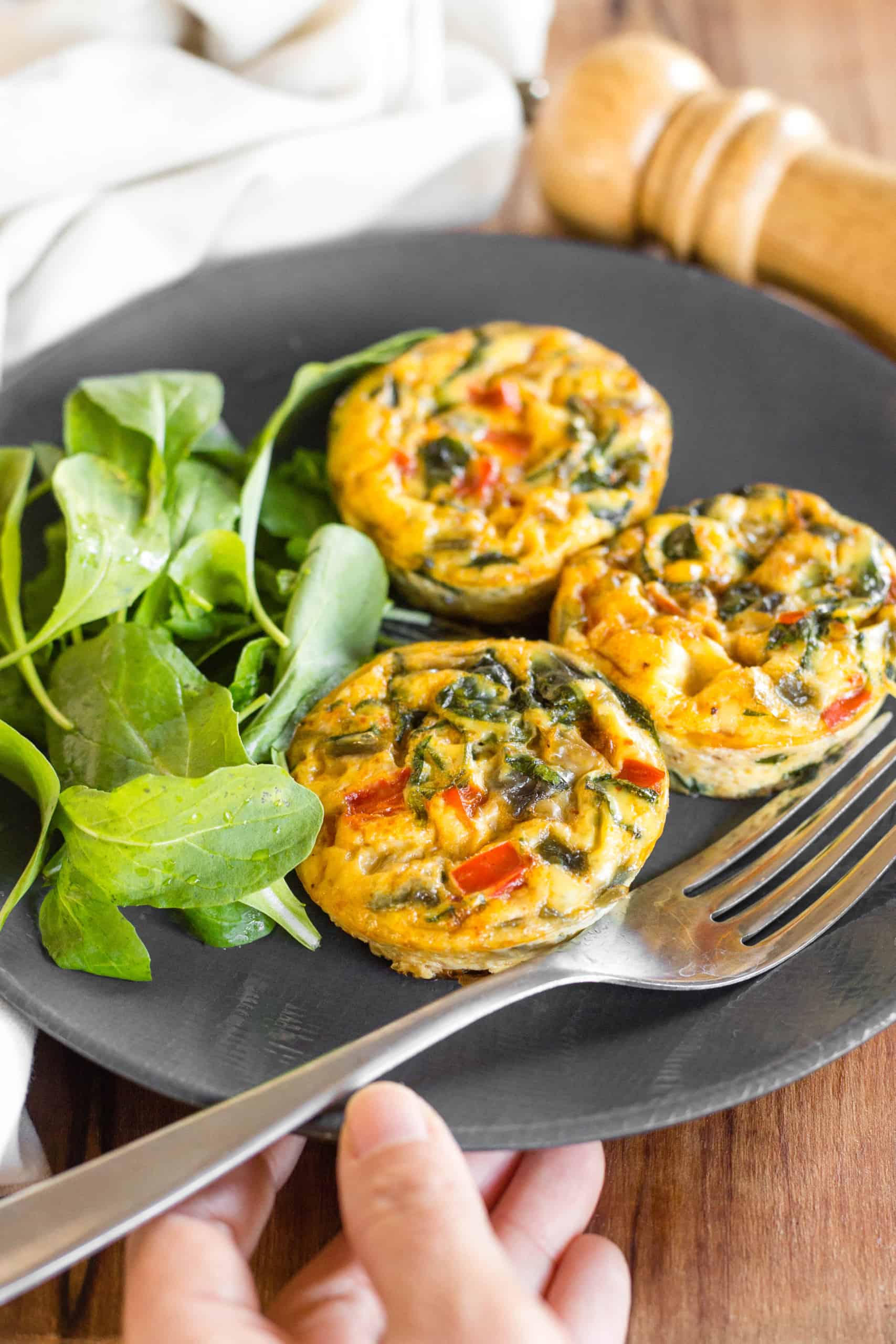 Holding a plate with crustless quiche cups and salad.