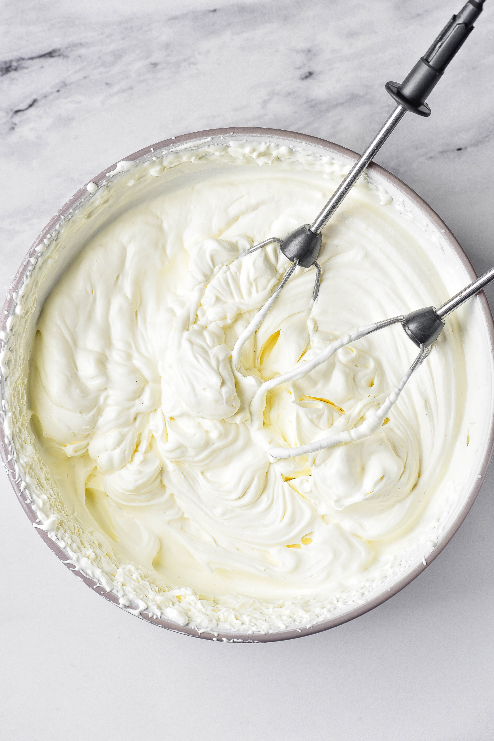 Whipped cream with beaters in bowl.