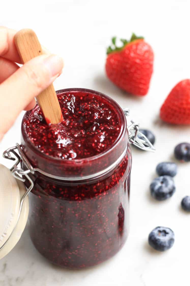 Hand mixing berry chia seed jam in a jar.