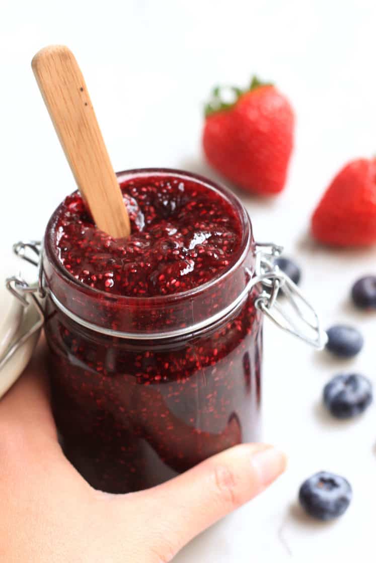 Hand holding a jar of mixed berry chia seed jam.