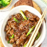 Top down view of a bowl of Mongolian beef and chopsticks