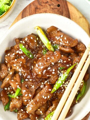 Top down view of a bowl of Mongolian beef and chopsticks