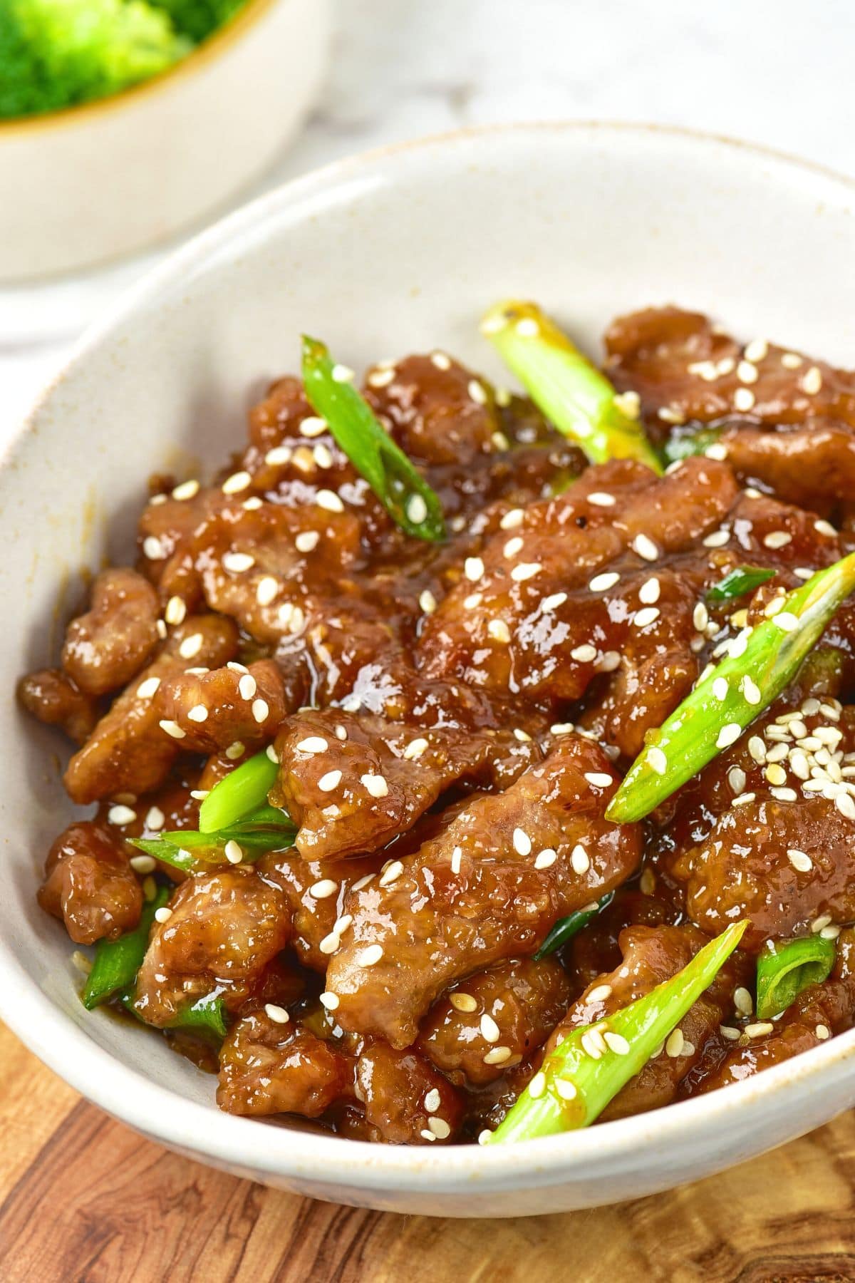 Up cloes view of a bowl of gluten-free mongolian beef on wooden board.