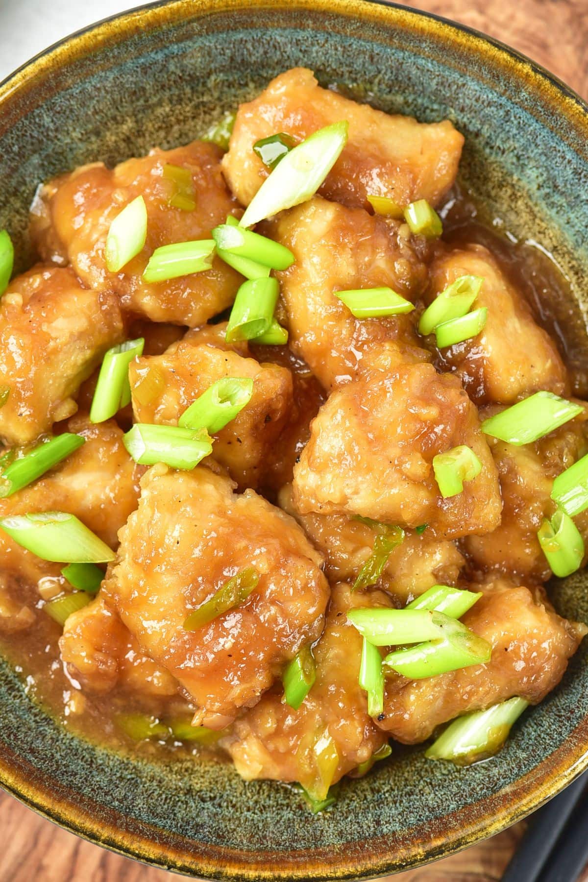 Top down view of a bowl of Mongolian chicken topped with green onions