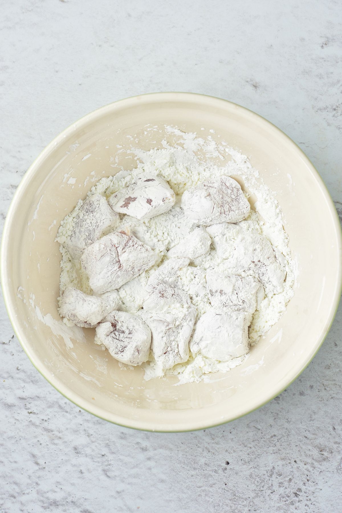 Tossing chicken cubes in cornstarch