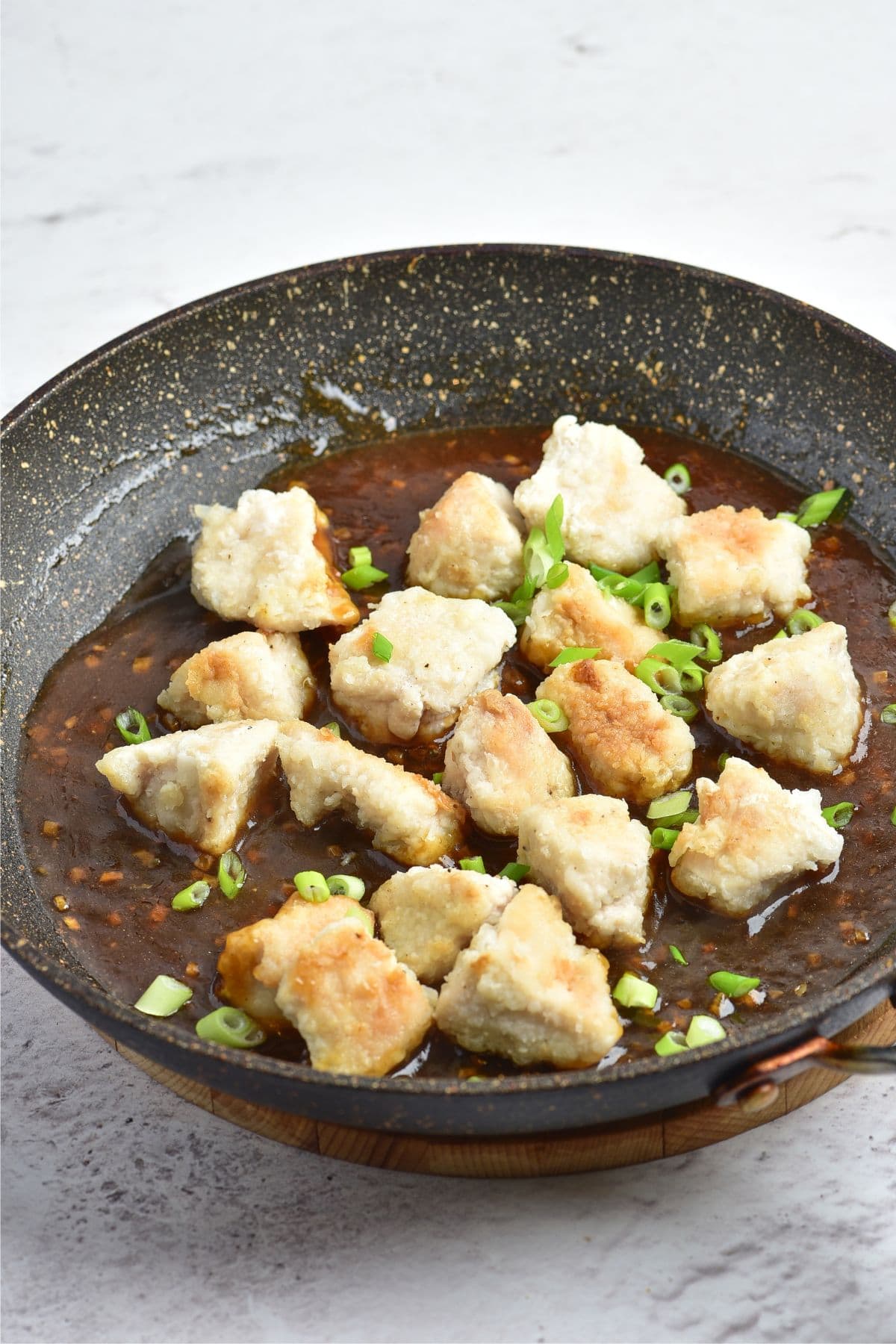 Fried chicken pieces in brown sauce in skillet