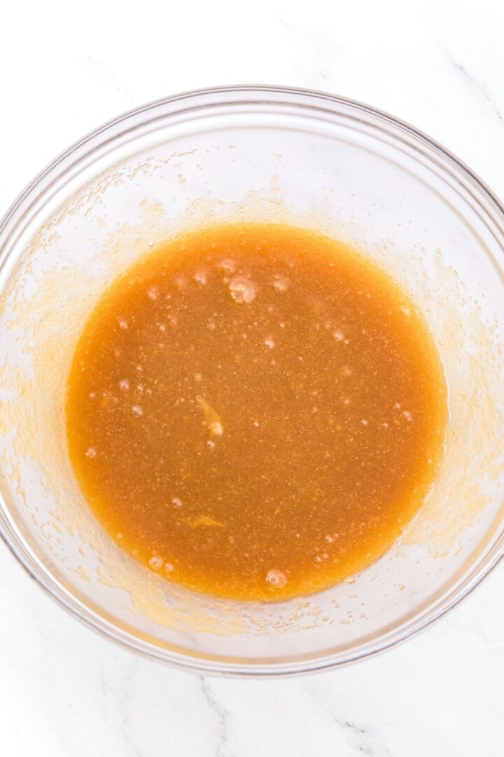 Brown viscous liquid in glass mixing bowl.