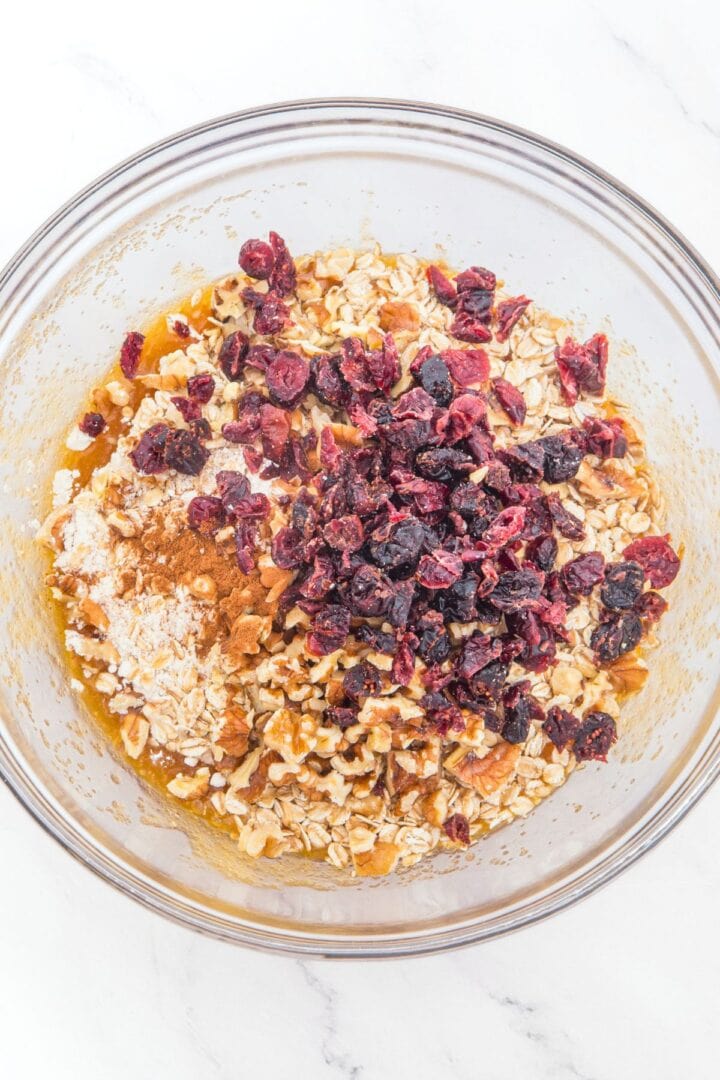 Oats, dried cranberries and spices on top of brown mixture.