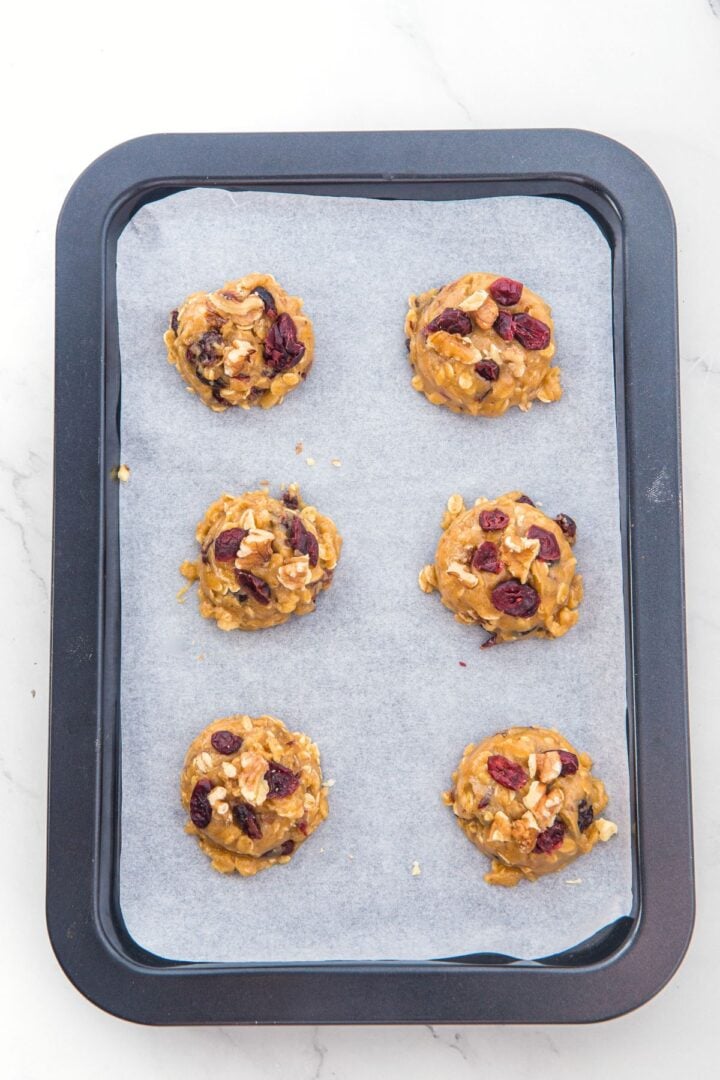 Cookie dough balls on parchment-lined baking sheet.