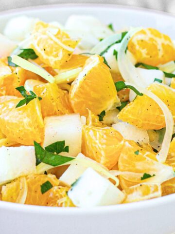 A bowl of orange and jicama salad topped with parsley
