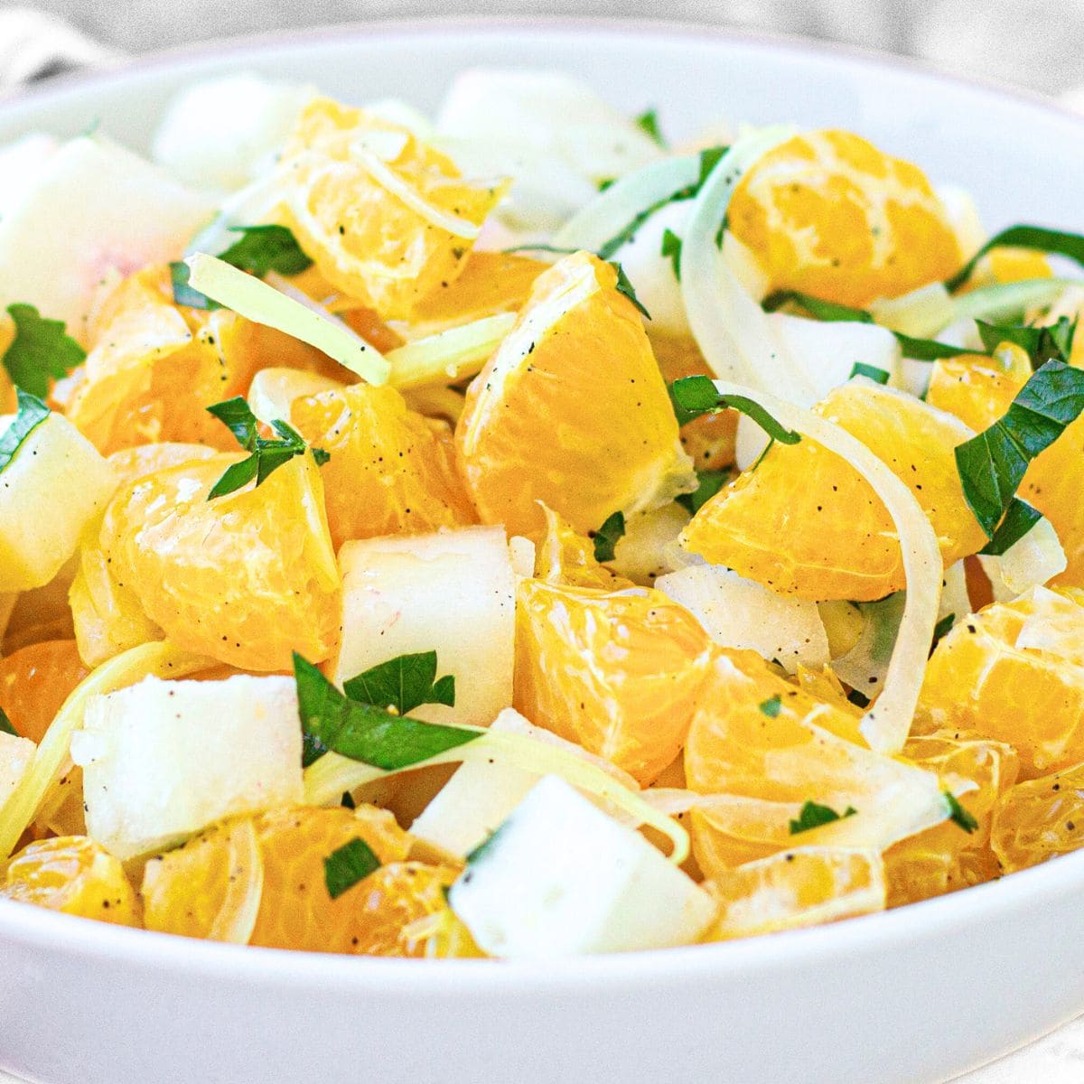 A bowl of orange and jicama salad topped with parsley