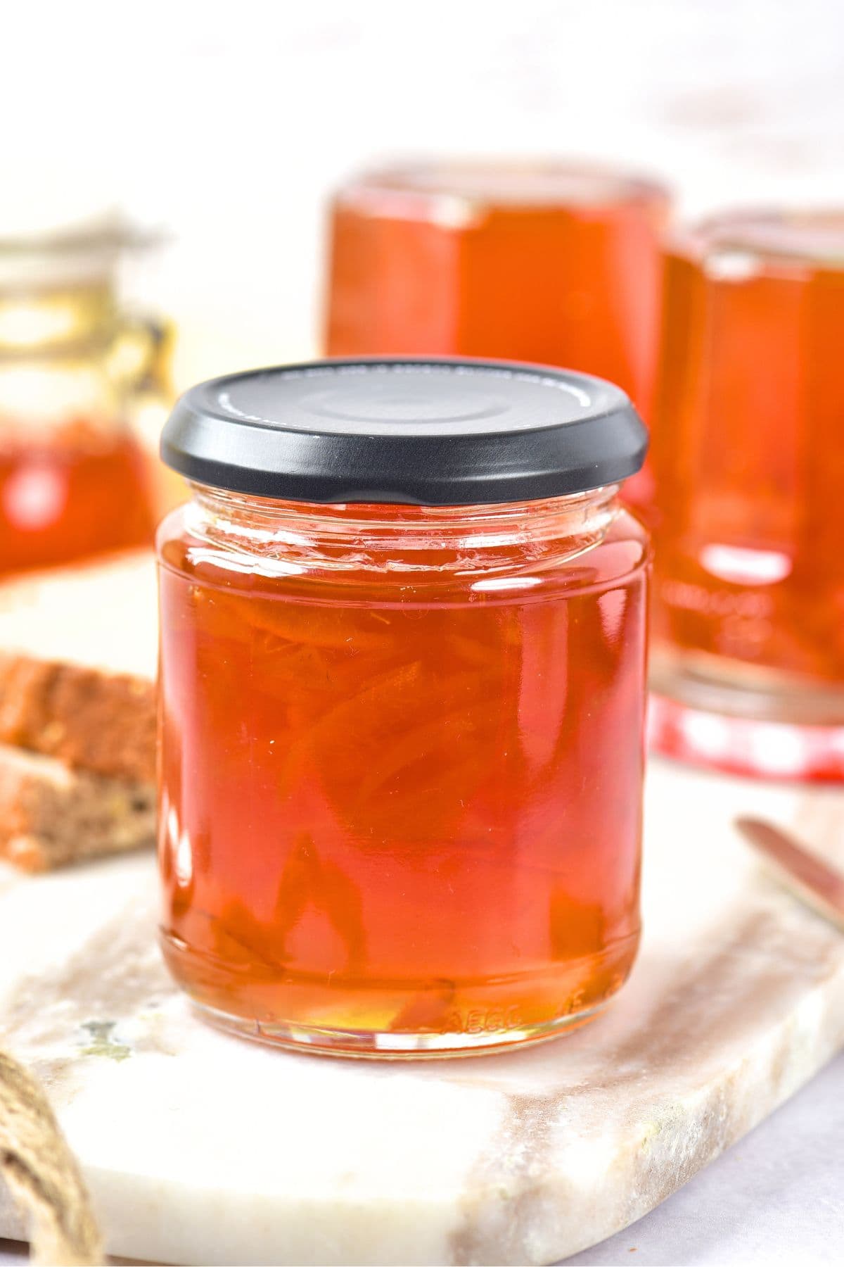 A jar of orange marmalade without pectin on marble board.
