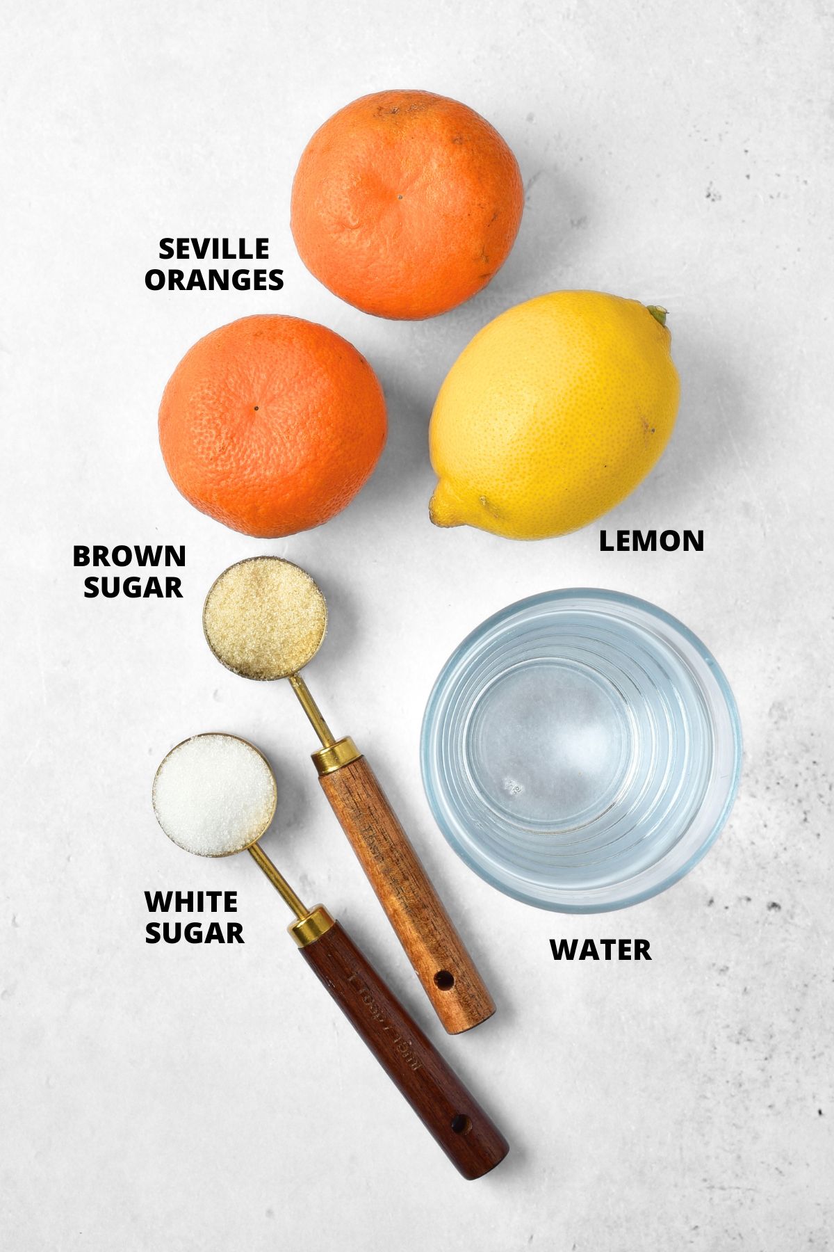 Ingredients for homemade orange marmalade recipe laid out on white board.