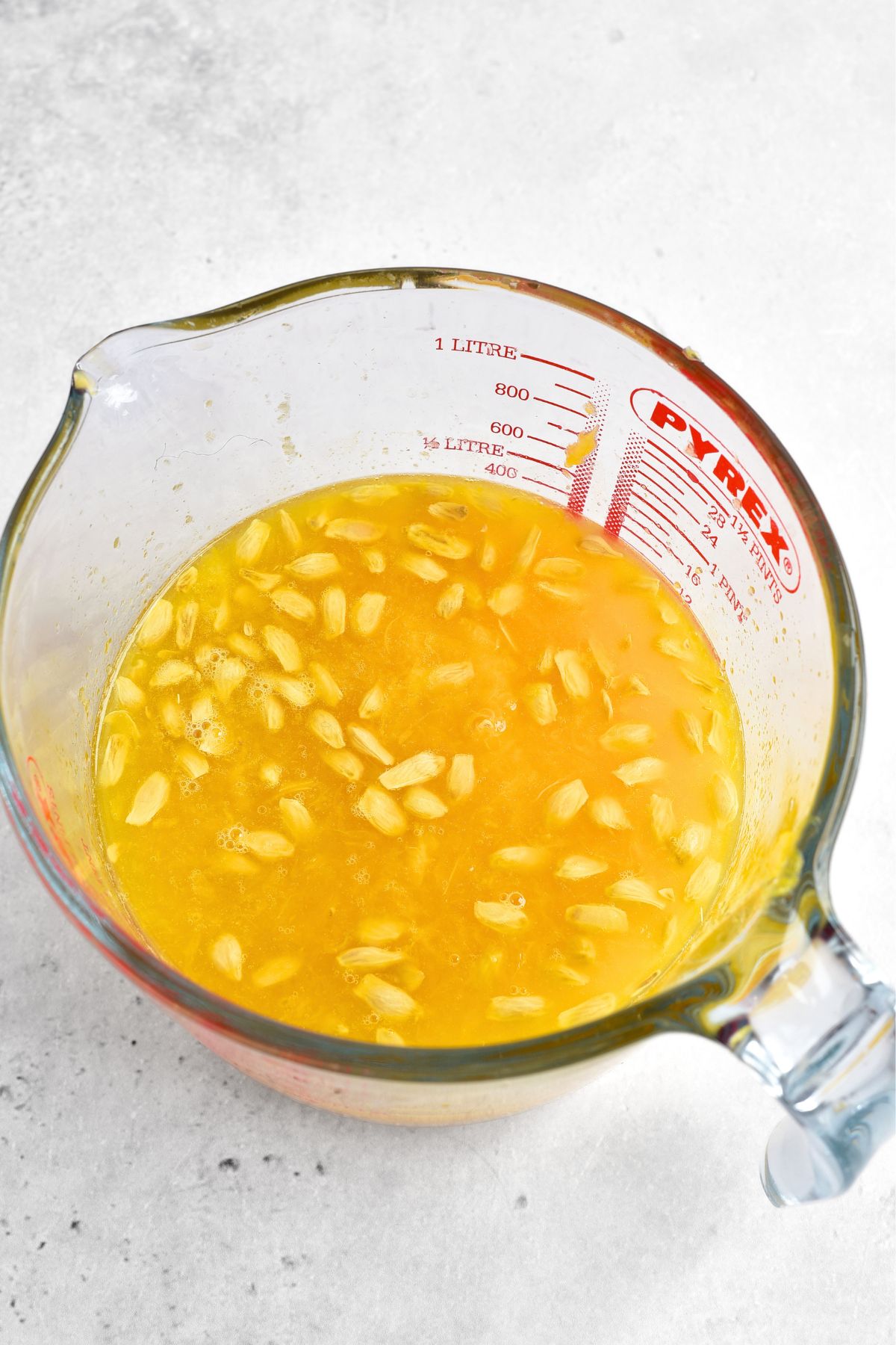 Orange juice and seeds in a measuring cup