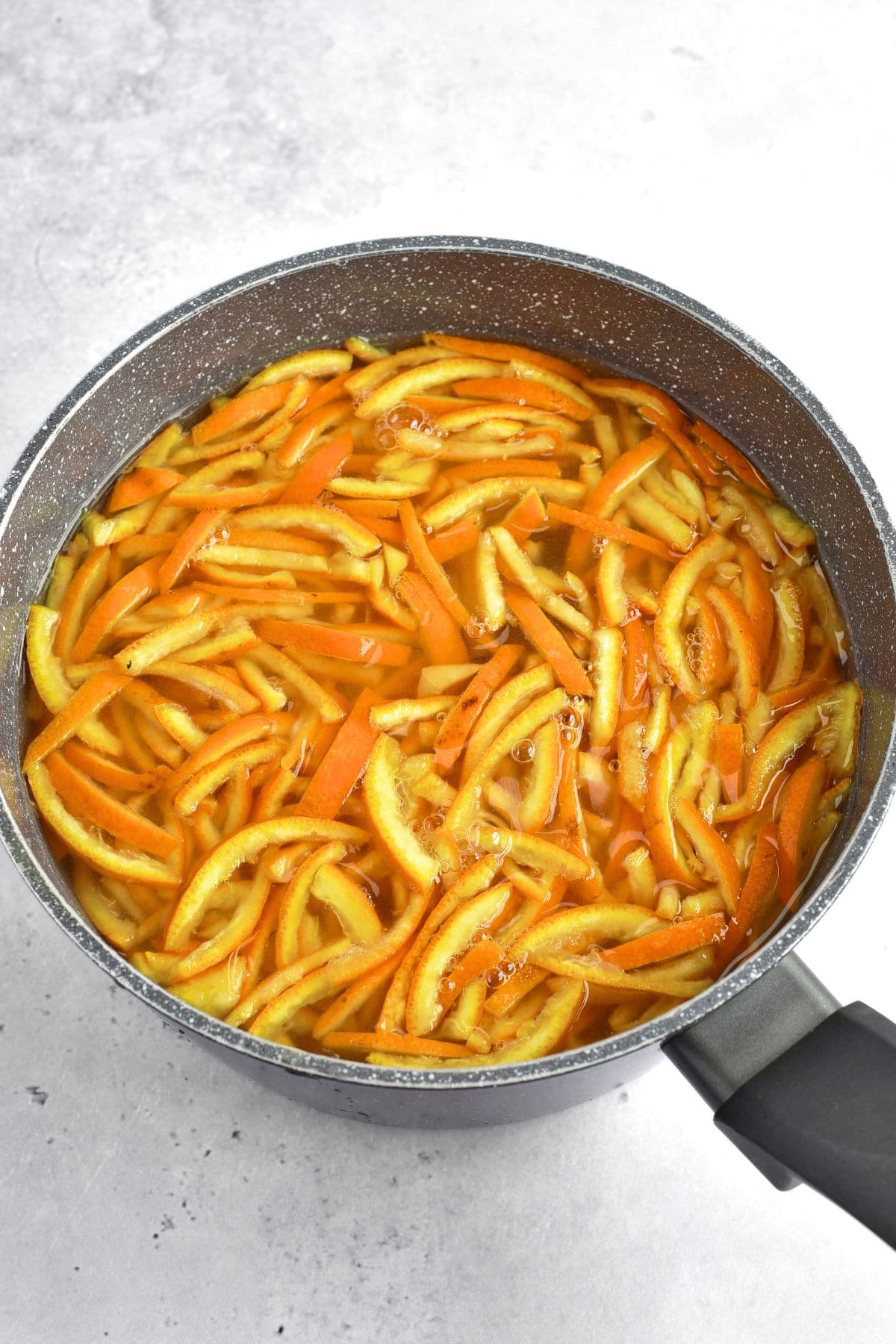 Boiling orange peel slices in a pot