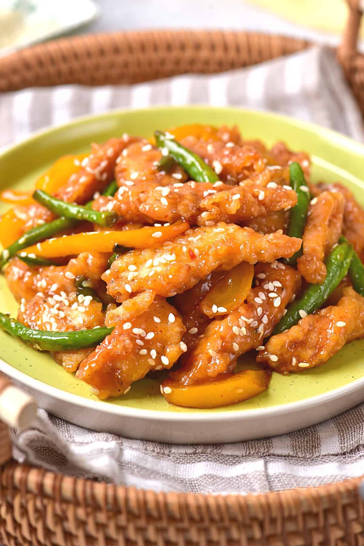 Up close view of a plate of honey sesame chicken and veggies.