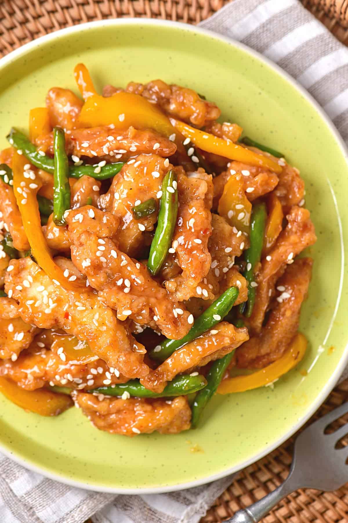 Up close shot of a plate of honey sesame chicken.