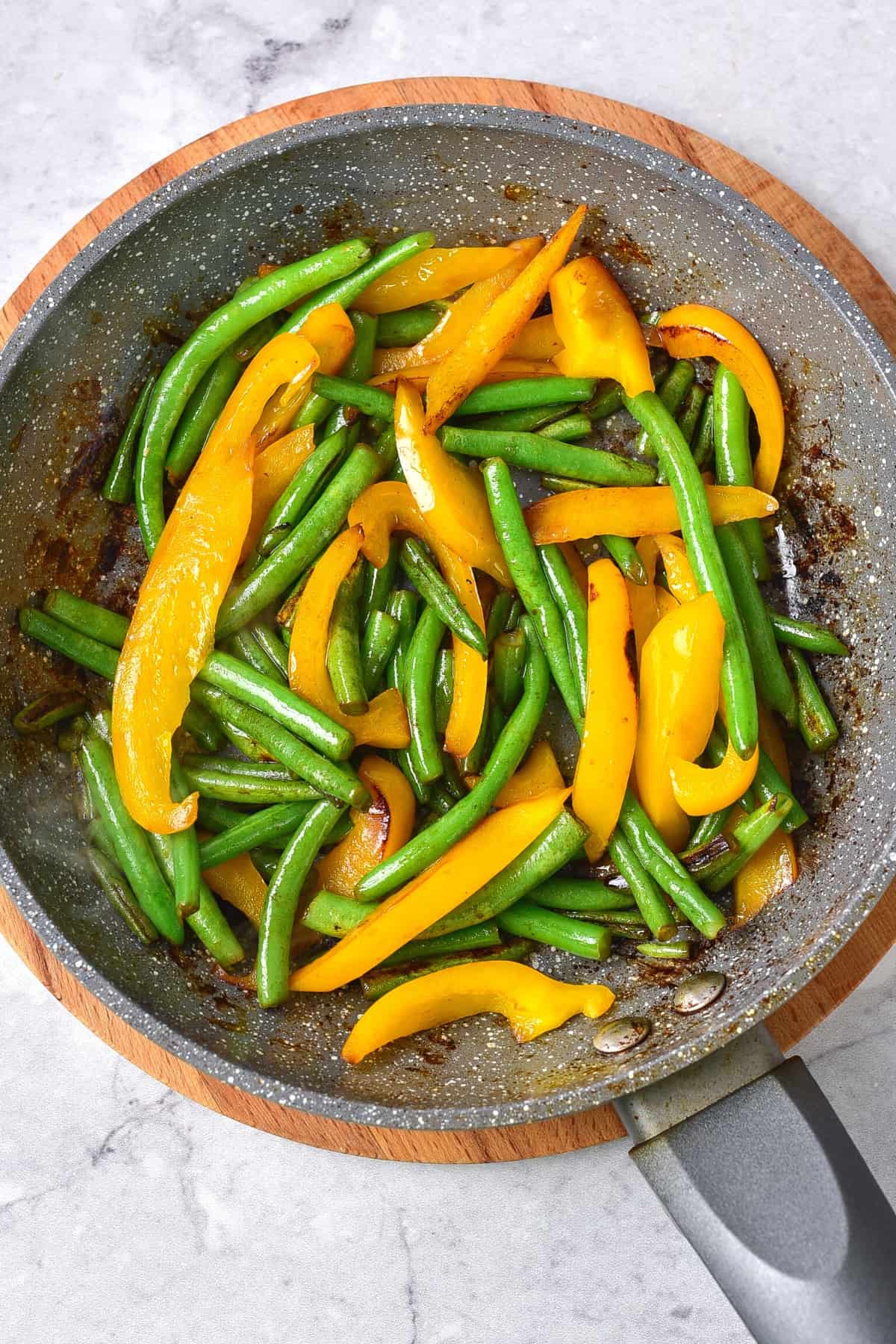 Stir-fried bell peppers and long beans in skillet.