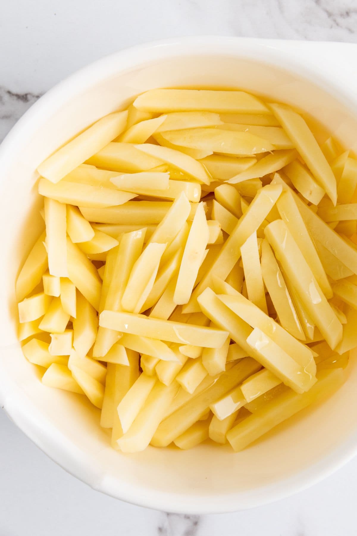 Cut potato fries soaking in a bowl of water.