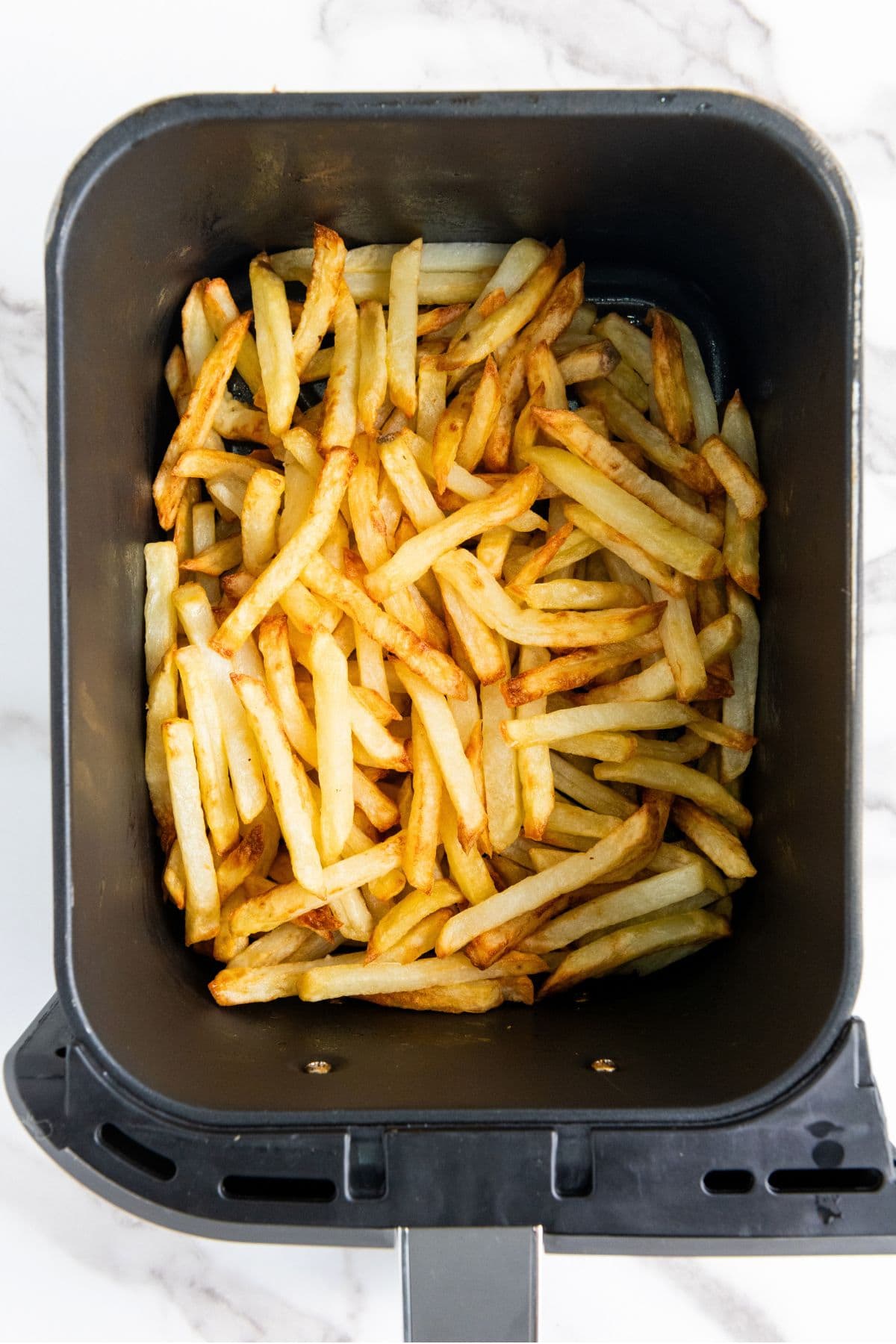 Freshly cooked french fries in air fryer basket
