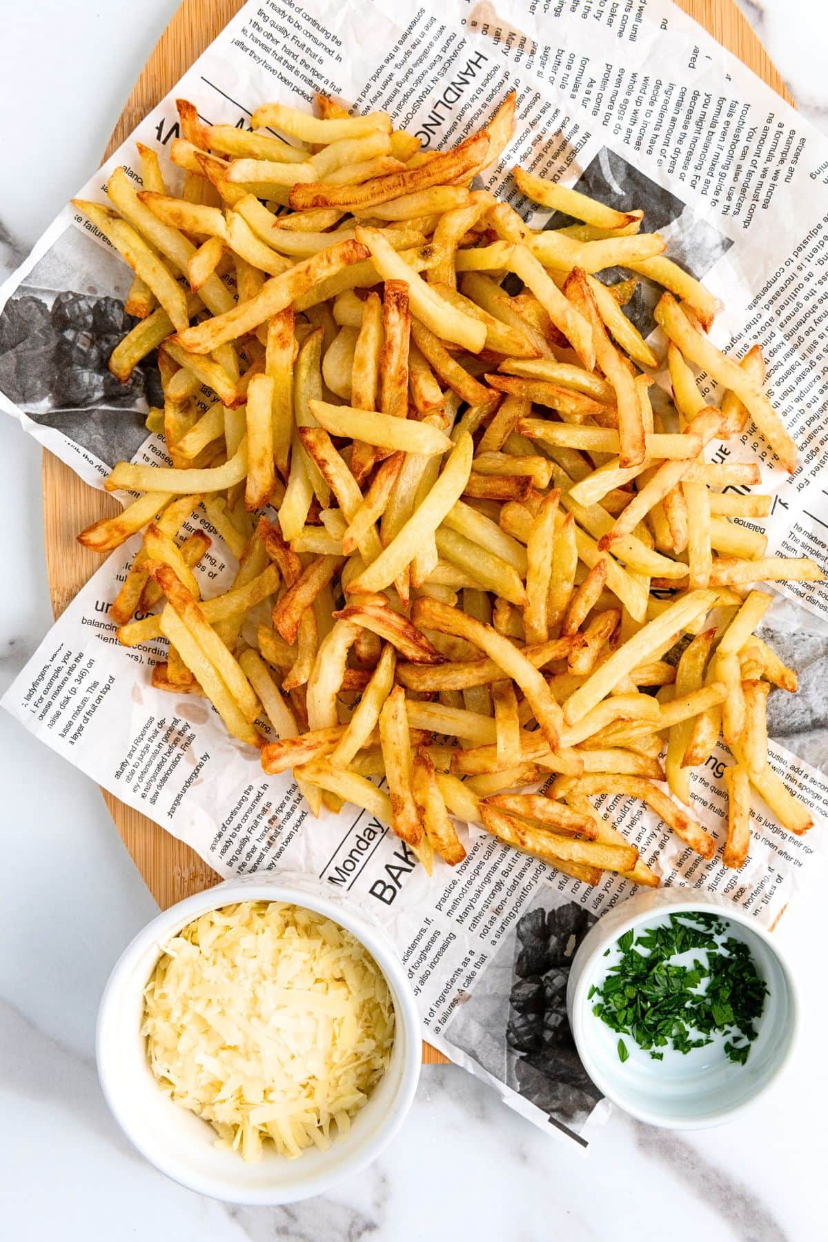 Top down view of truffle and parmesan fries with small bowls of cheese and parsley.
