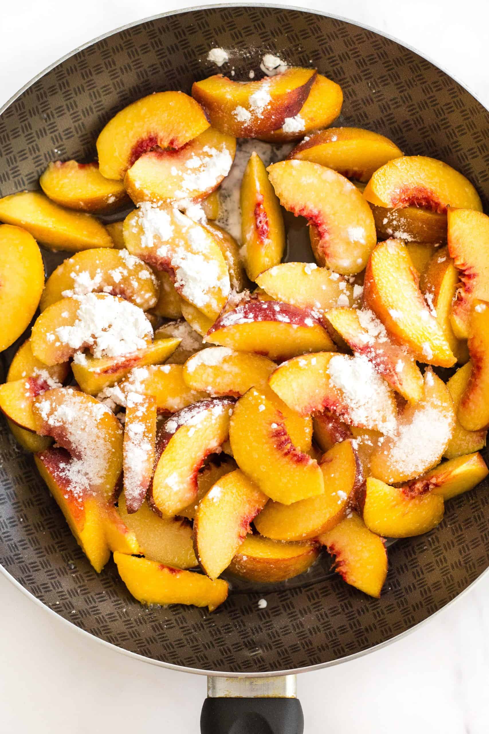 Sliced peaches and corn starch in a skillet.