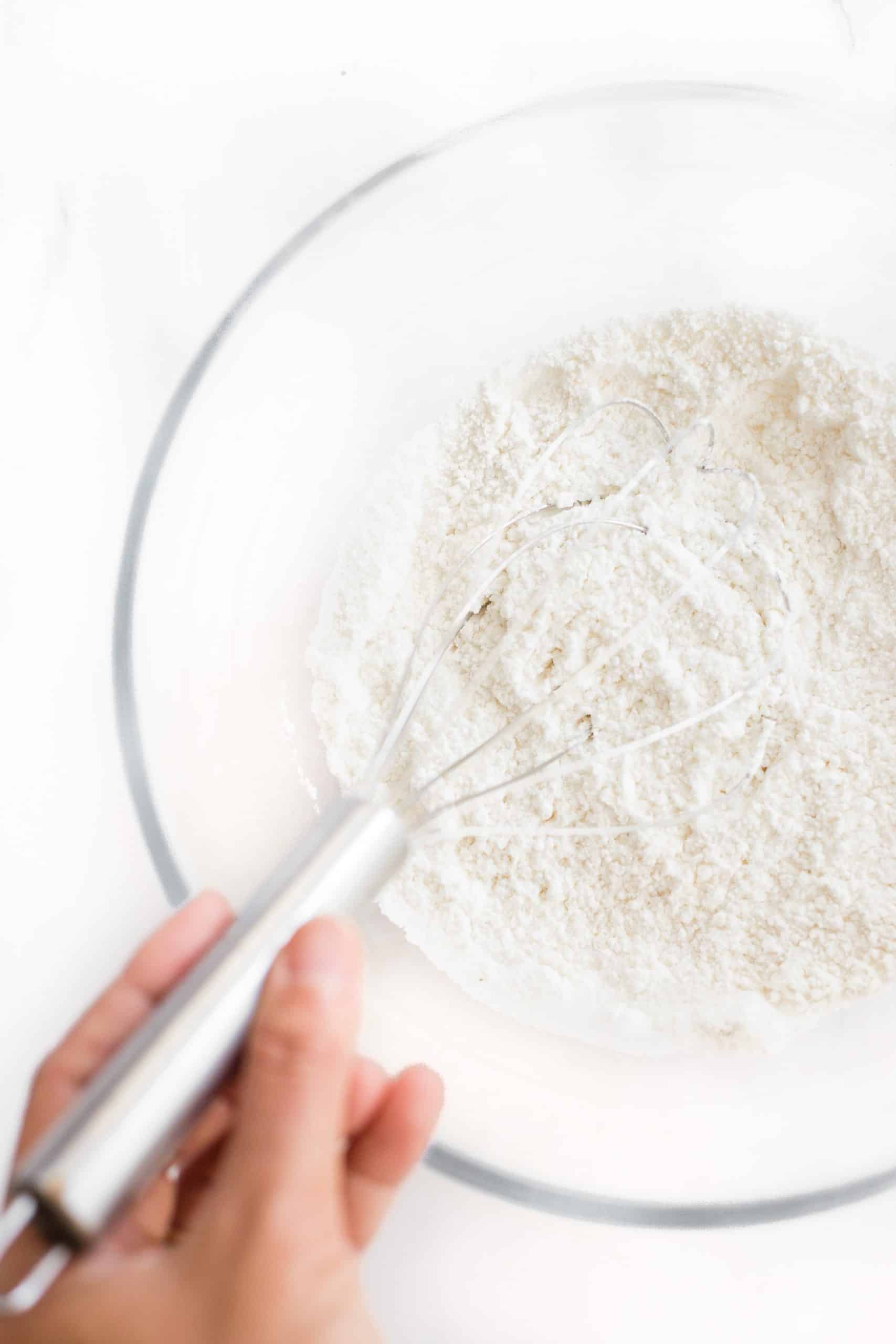 Whisking dry ingredients in a large glass bowl.