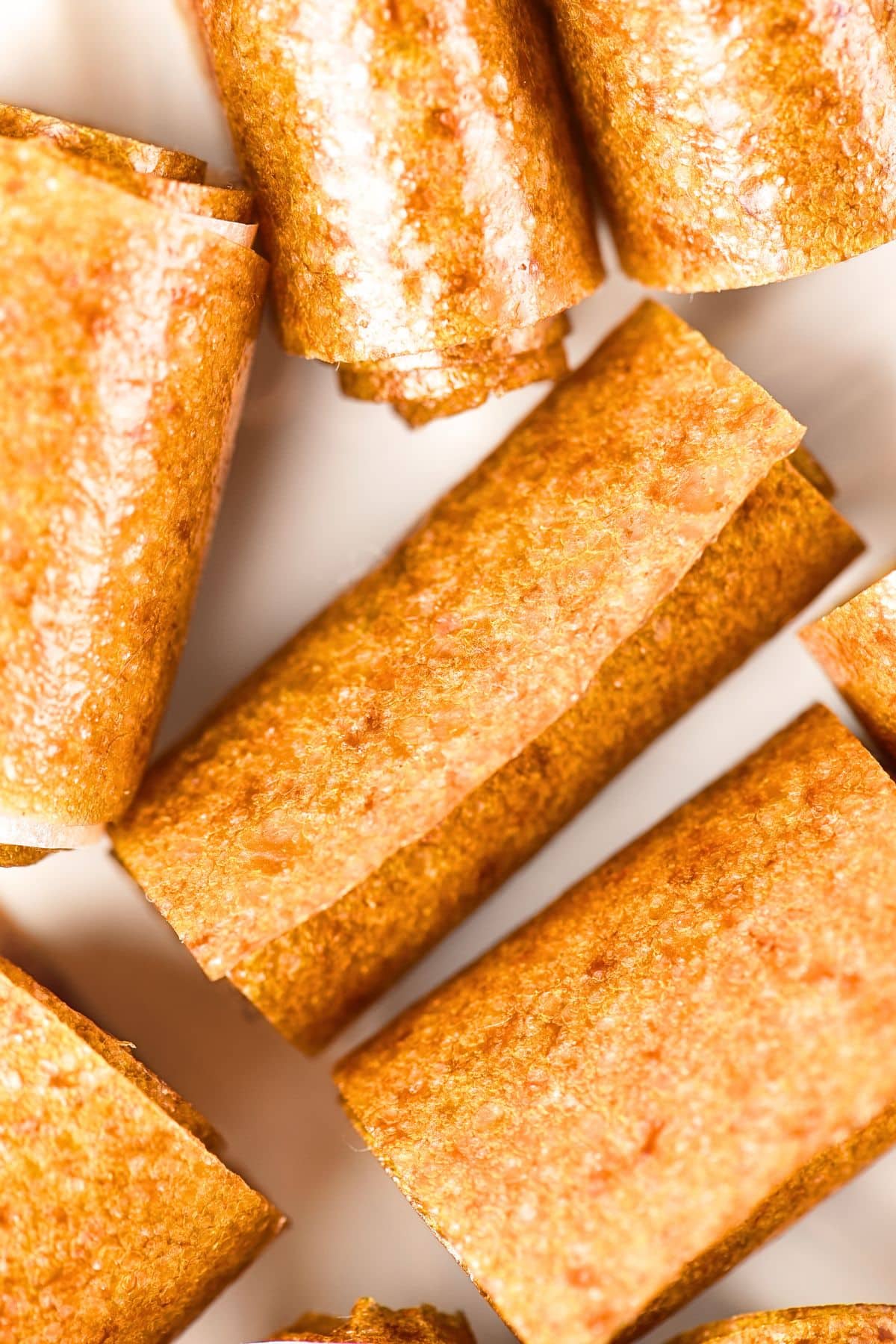Top down view of rolls of peach fruit leather on plate.