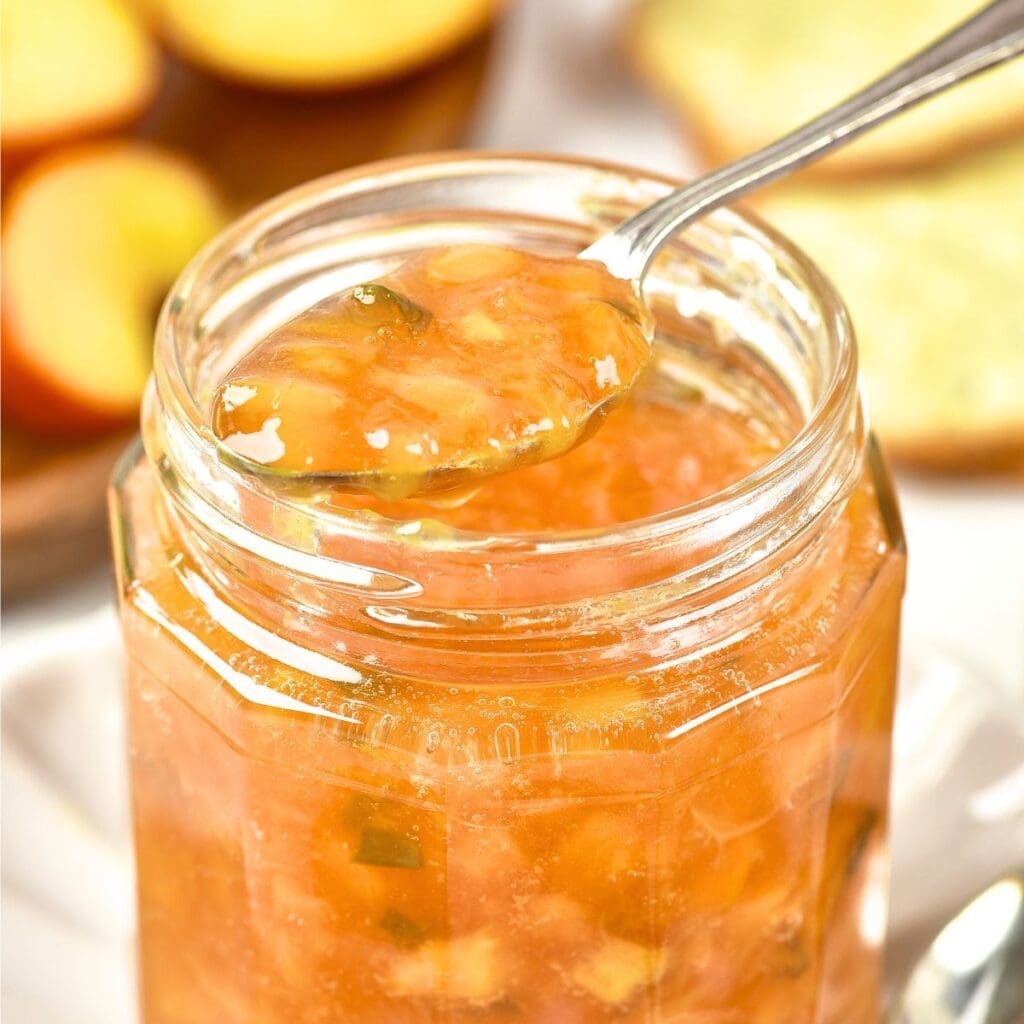 Holding up a spoonful of peach jalapeno jam